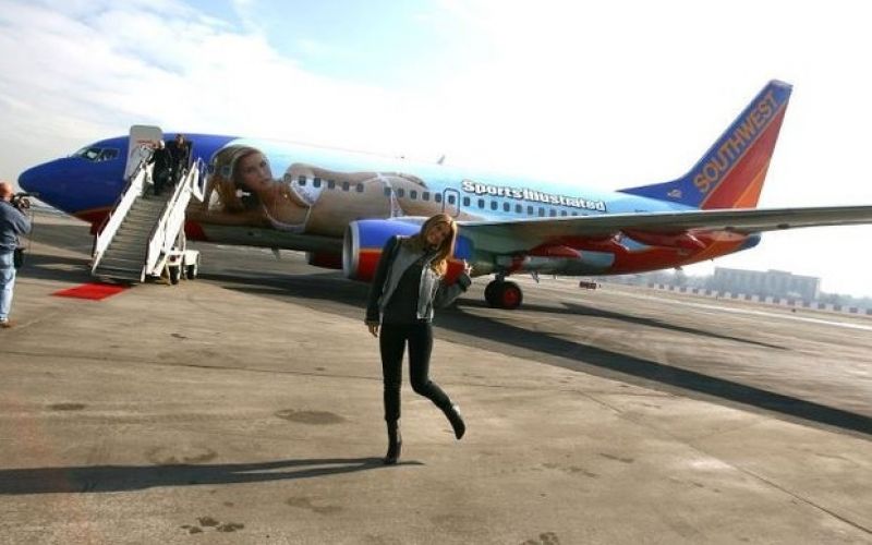 Modelo Bar Refaeli posa em frente a avião pintado com sua foto